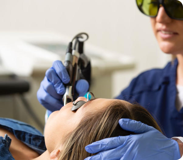 a woman holding a laser probe up next to another woman laying down.